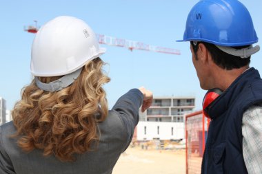 Tradesman and an engineer working together on a construction site clipart