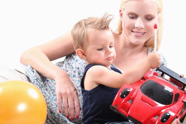 Mamãe e seu filho brincando com carro de brinquedo — Fotografia de Stock