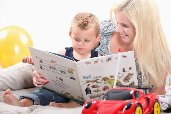 Een moeder en haar baby op zoek naar een boek — Stockfoto