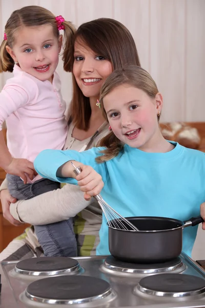 母亲和两个年幼的女儿做饭 — 图库照片