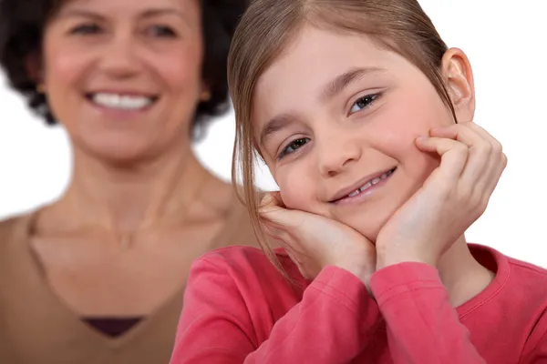 Malá dívka pózuje s matkou všech úsměvy v pozadí — Stock fotografie