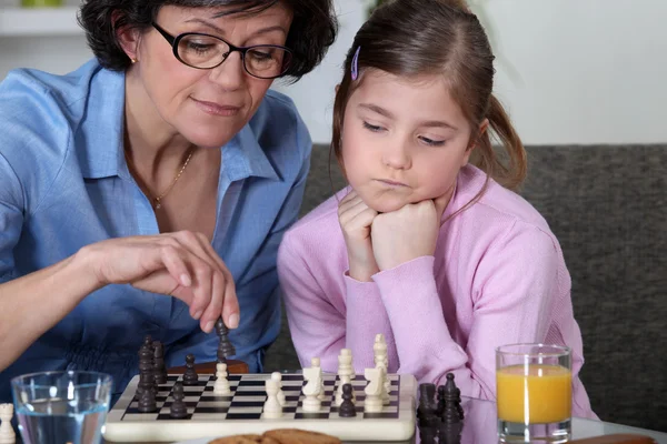 Молодая девушка играет в шахматы с бабушкой — стоковое фото