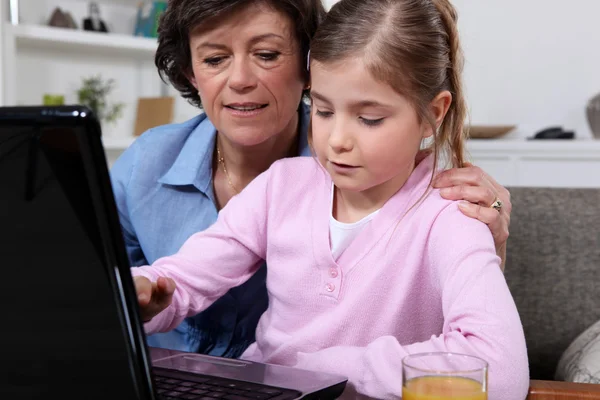 Senior vrouw en meisje werken op laptopcomputer — Stockfoto