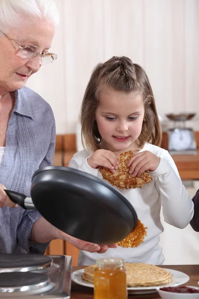 Grandmother and granddaughter making pancakes — Stock Photo, Image