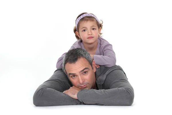 Una bambina sdraiata sulla schiena di suo padre . — Foto Stock