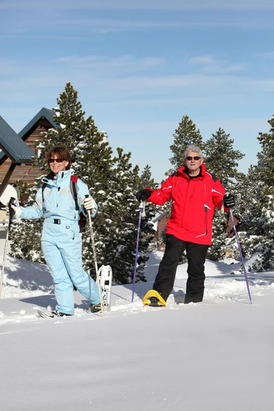 Älteres Paar spaziert in Schneeschuhen — Stockfoto