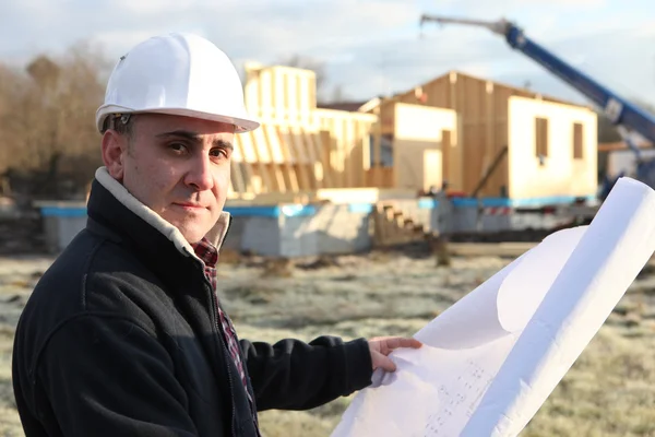 Arquitecto de pie con la casa inacabada en la distancia — Foto de Stock