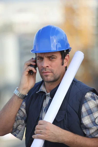 Trabalhador da construção civil no local com um telefone — Fotografia de Stock