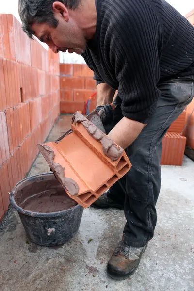 Mason espalhando cimento no tijolo — Fotografia de Stock