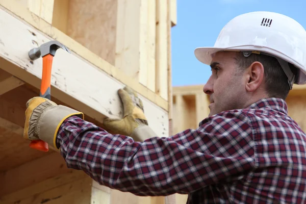Worker nailing wooden framed house — Stock Photo, Image