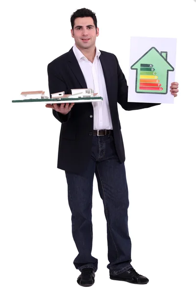 Joven arquitecto holding modelo muestra energía clasificación casa — Foto de Stock