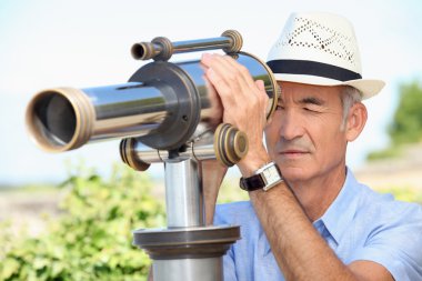 Senior man looking through a telescope clipart