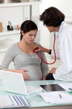 Pregnant woman at a doctor's surgery clipart