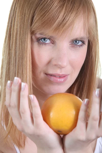 Женщина берет апельсин в руки — стоковое фото