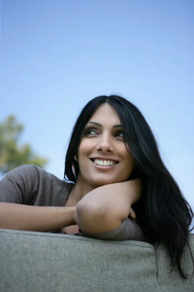 Aantrekkelijke brunette zoon op een sofa in de tuin — Stockfoto