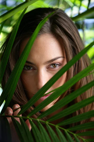 Woman hiding behind plant leaves — Stock Photo, Image