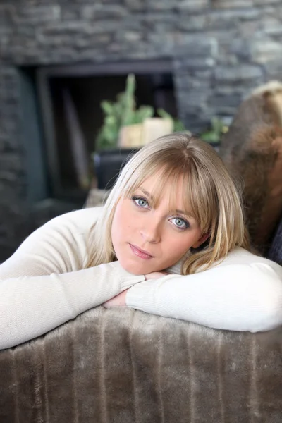 Portrait of good-looking young blonde in chalet with face resting in arms — Stock Photo, Image