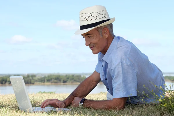 Homme avec ordinateur au bord de la rivière — Photo