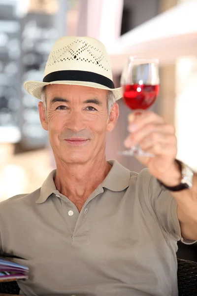 Elderly man toasting with glass of rose wine — Stock Photo, Image