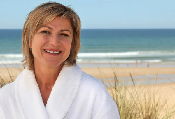 Vrouw met een badjas op het strand — Stockfoto
