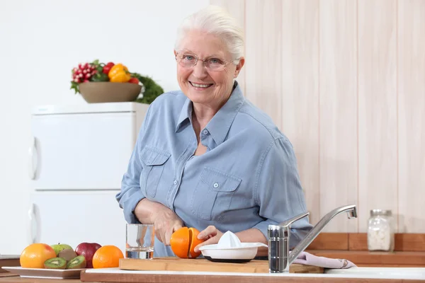 Dame âgée coupant une orange — Photo