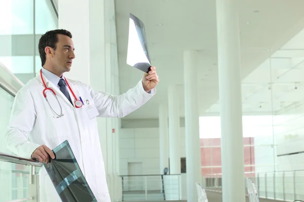 Dottore in piedi nel corridoio esaminando i raggi X — Foto Stock