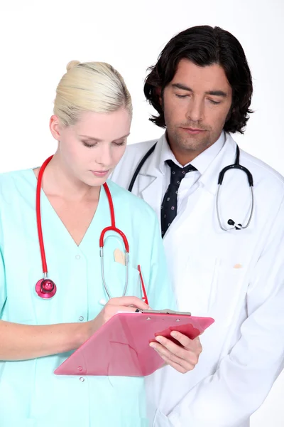 En läkare och en sjuksköterska söker seriöst ett papper — Stockfoto