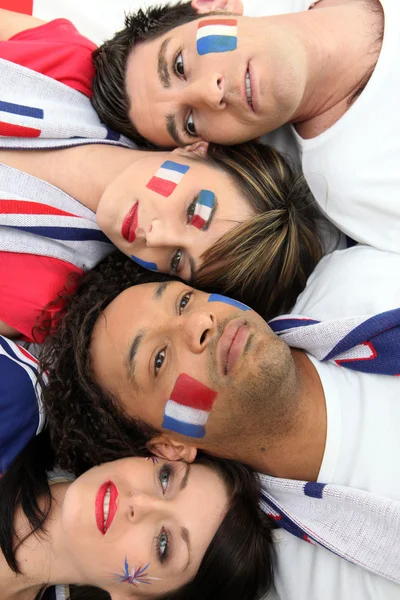 Quatro fãs de esportes franceses deitados juntos — Fotografia de Stock