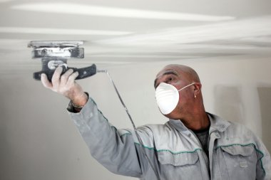 Man putting up a plasterboard ceiling clipart