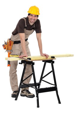 Man sawing wood on workbench clipart