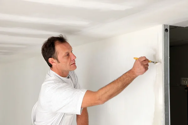 Homem pintando toques finais na parede — Fotografia de Stock