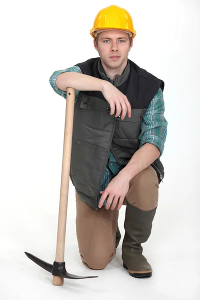 Mann mit Spitzhacke kniet — Stockfoto
