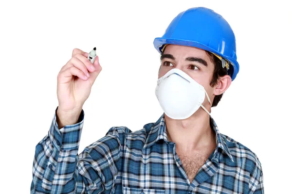 Trabalhador usando uma máscara facial e segurando uma caneta de feltro — Fotografia de Stock