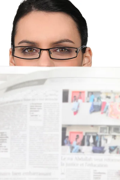 Mujer con gafas mirando un periódico — Foto de Stock