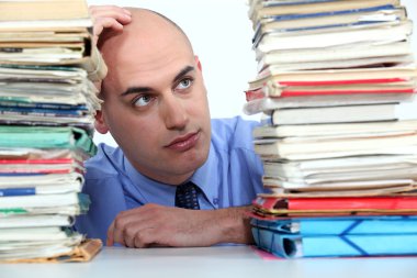 Office worker looking at stacks of files clipart