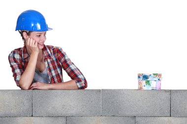 Tradeswoman staring at a house made out of money clipart