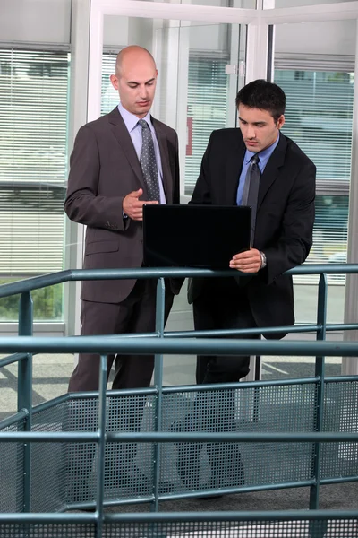 Hommes d'affaires debout dans un couloir avec ordinateur portable — Photo