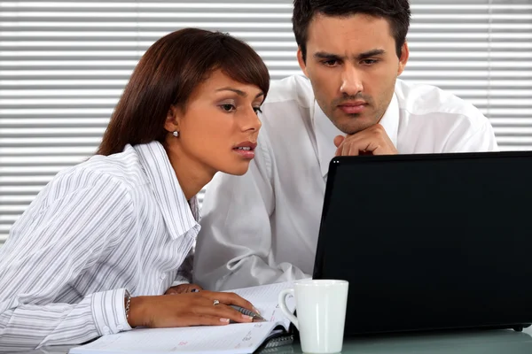 Pareja de negocios sentada en un portátil — Foto de Stock