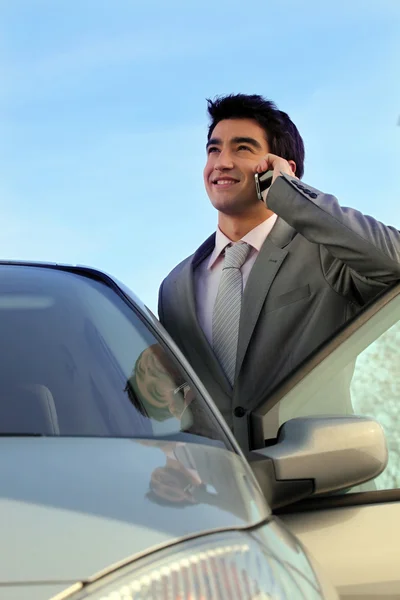 Бізнесмен стояв біля своєї машини, роблячи телефонний дзвінок — стокове фото