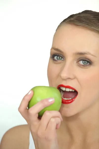 Женщина кусается в зеленое яблоко — стоковое фото