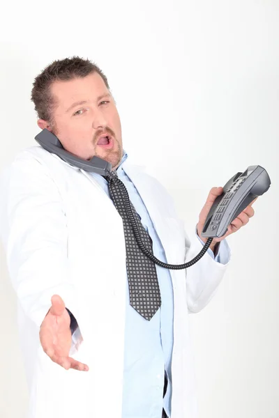Médico oferecendo para apertar a mão enquanto no telefone — Fotografia de Stock