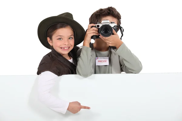 Fotógrafos de imprensa infantil com uma placa deixada em branco para sua mensagem — Fotografia de Stock