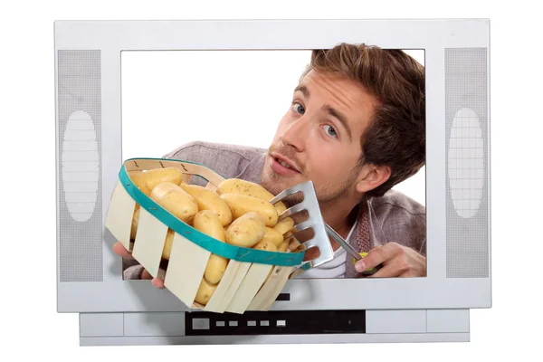 Hombre con papas nuevas y un tenedor de jardín atrapado en un televisor —  Fotos de Stock