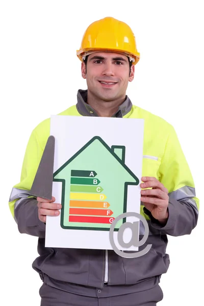 Un trabajador de la construcción sostiene una paleta, un signo de clasificación eficiencia energética y al símbolo — Stockfoto