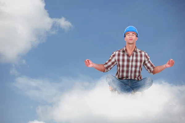 Laborer doing yoga sitting on a cloud — Stock Photo, Image