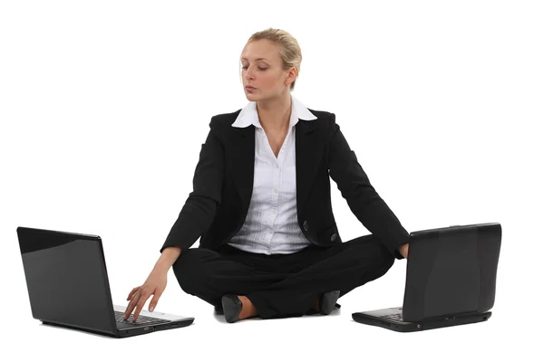Blond businesswoman sat with two laptops Stock Picture