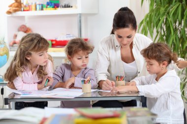 Woman helping a group of girls with their homework clipart