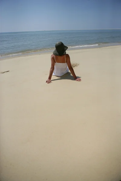 Kvinnan sitter på en strand — Stockfoto