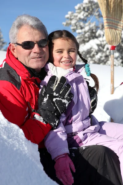 Дедушка и маленькая девочка на лыжных каникулах — стоковое фото