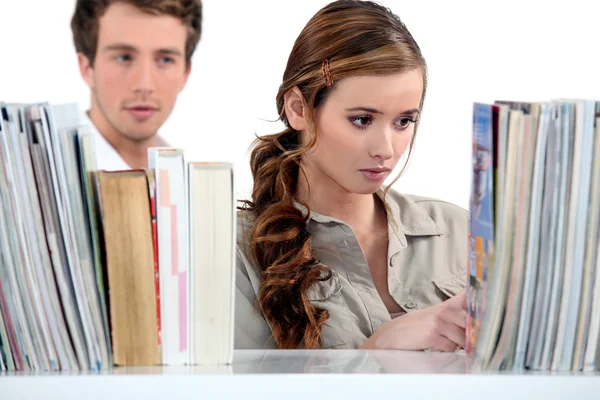 Jonge vrouw in de openbare bibliotheek en man in de achtergrond — Stockfoto